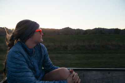 Woman sitting on field against clear sky