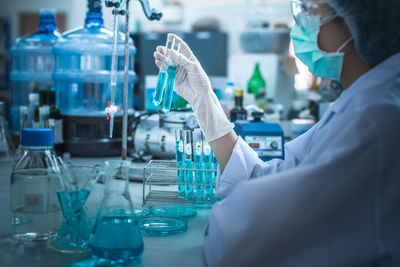 Scientist holding test tubes at table in laboratory