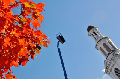 Low angle view of maple tree by tower against clear blue sky