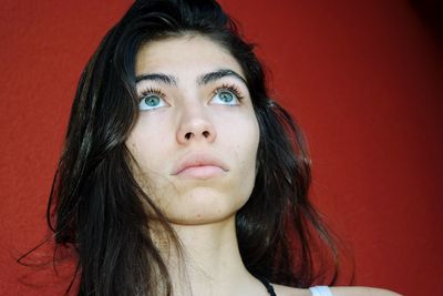 Close-up of beautiful young woman looking away while standing against wall