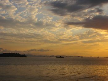 Scenic view of sea against cloudy sky at sunset