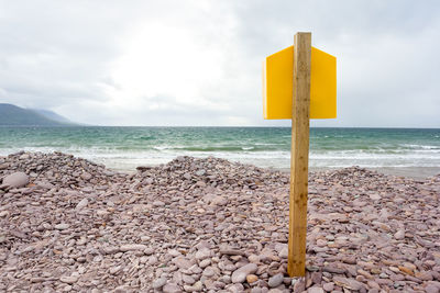 Yellow wooden posts on beach against sky