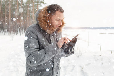 Man holding smart phone while standing on snow