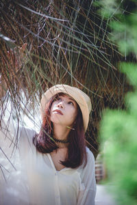 Portrait of beautiful young woman standing against trees