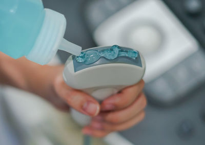 Midsection of person pouring gel on ultrasound machine at hospital