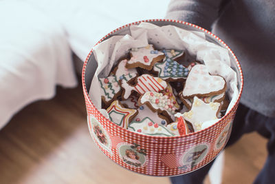 Midsection of person with cookies in container standing at home