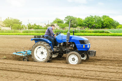 A white caucasian farmer on a tractor making rows on a farm field. preparing the land for planting 