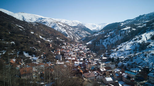 Aerial view of villagescape and mountains against clear sky