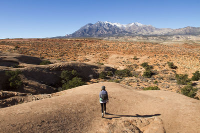 High angle view of hiker walking on field against clear blue sky