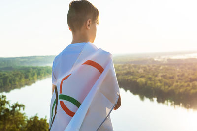 Rear view of man standing by lake against sky