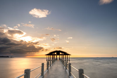 Pier over sea against sky during sunset