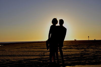 Rear view of man and woman standing at beach