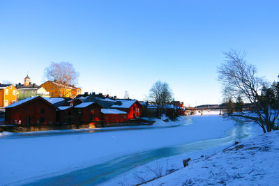 Houses by snow covered trees against sky