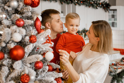 Young parents play with little son. happy family having fun at home near christmas tree