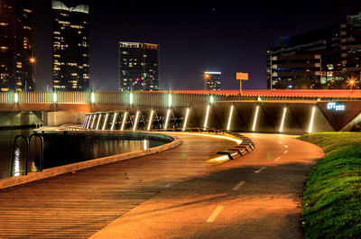 Illuminated bridge by buildings in city at night
