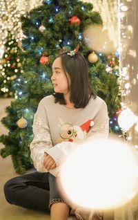 Portrait of young woman with christmas tree at home