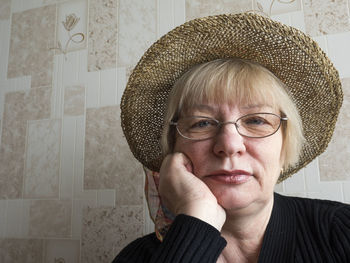Portrait of senior woman wearing wicker hat against tiled wall
