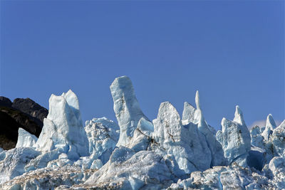 Low angle view of snow against clear blue sky