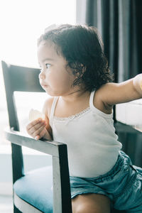 Cute girl sitting on chair at home