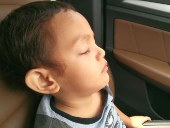 Close-up of cute boy sleeping in car