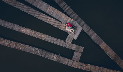 High angle view of couple lying on pier over lake