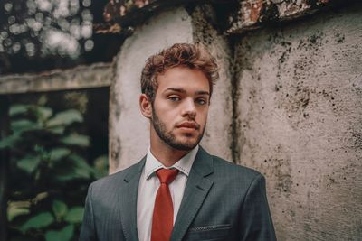 Portrait of young man standing against wall