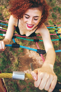 High angle view of happy young woman climbing on rope at playground