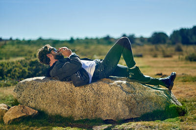 Portrait of young tattoed man lying on a rock smoking