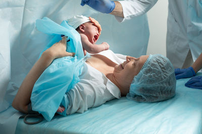 High angle view of doctor examining patient on bed