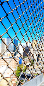 Close-up of chainlink fence against blue sky