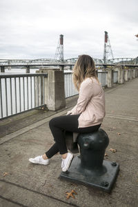 Woman sitting on suspension bridge