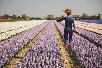 Rear view of woman jumping in flower field