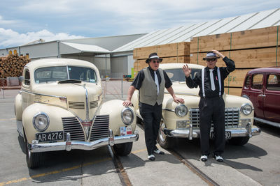 Portrait of friends standing by car