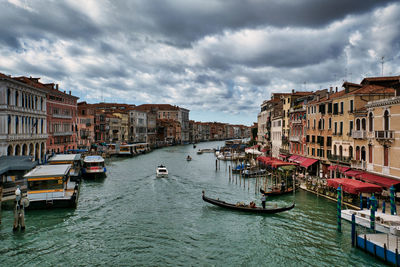 Boats in canal amidst buildings in city against sky