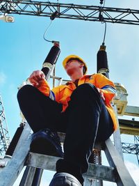 Low angle view of worker against sky