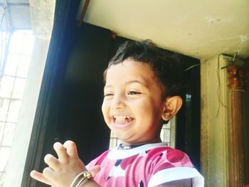 Close-up of cute smiling girl by window at home