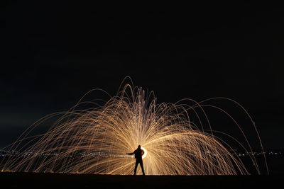 Man standing against wire wool at night