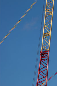 Low angle view of rollercoaster against clear blue sky