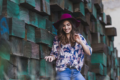 Portrait of smiling young woman standing against brick wall