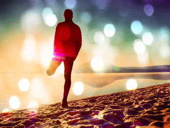 Rear view of woman standing against illuminated lights