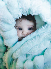 Portrait of cute baby lying on bed wrapped in blanket