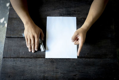 Midsection of person holding paper on table