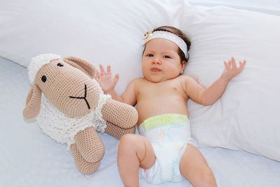 High angle view of baby with toy lying on bed
