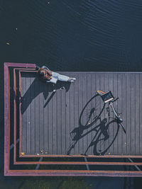 Aerial view of young woman reading book at edge of coastal jetty