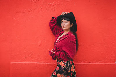 Dark-haired female model in vintage clothing and make-up against a colorful wall.