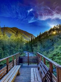 Wooden footbridge leading towards mountains against sky