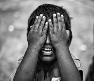 Close-up of boy covering eyes with hands