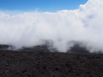 Scenic view of steam emitting from volcanic landscape against cloudy sky