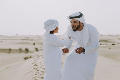 Smiling father and son enjoying while standing in desert