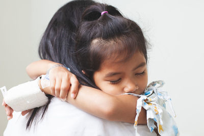 Mother carrying sick daughter against wall in hospital